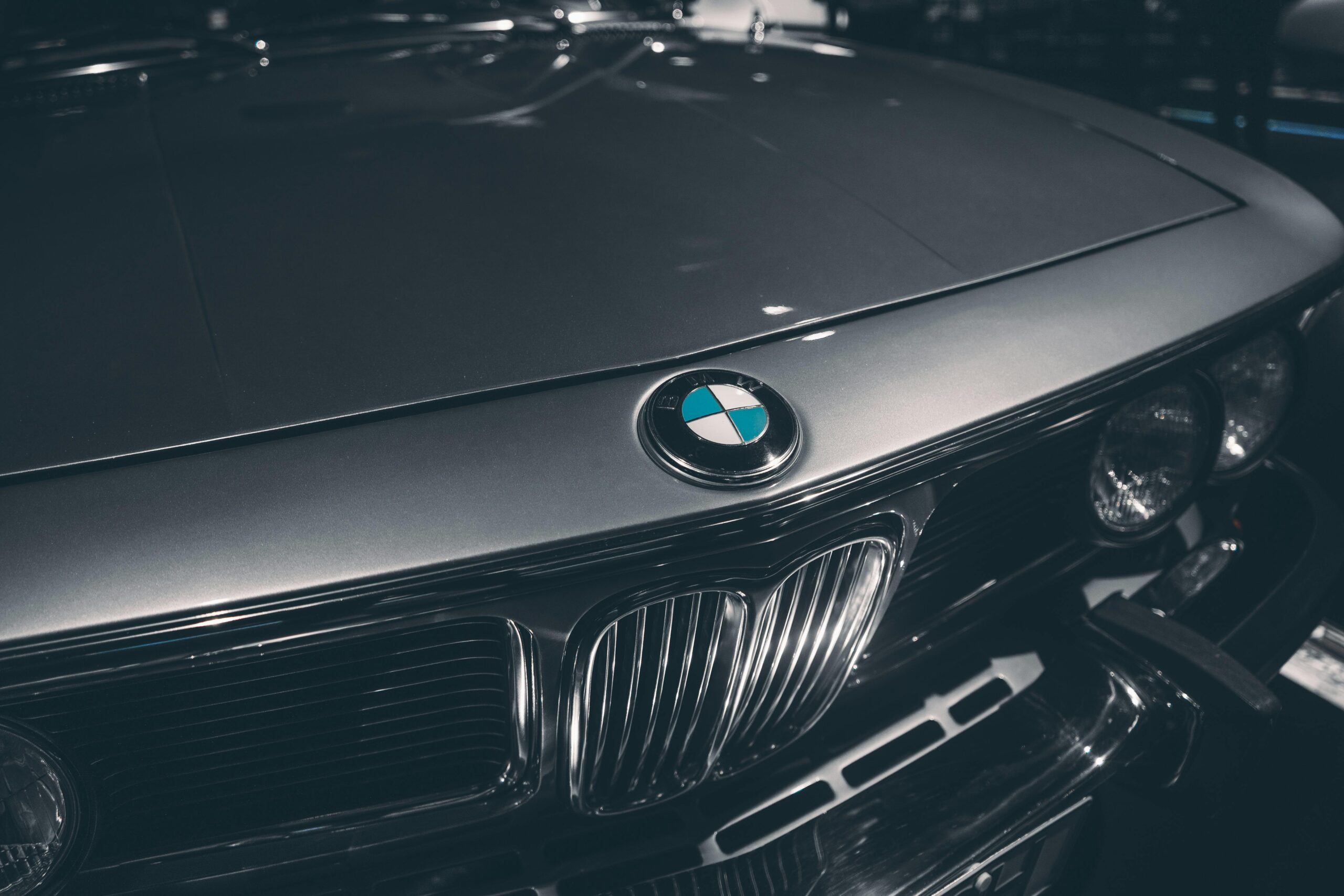 Close-up of classic BMW hood showcasing emblem and chrome details. Captured in Munich, Germany.